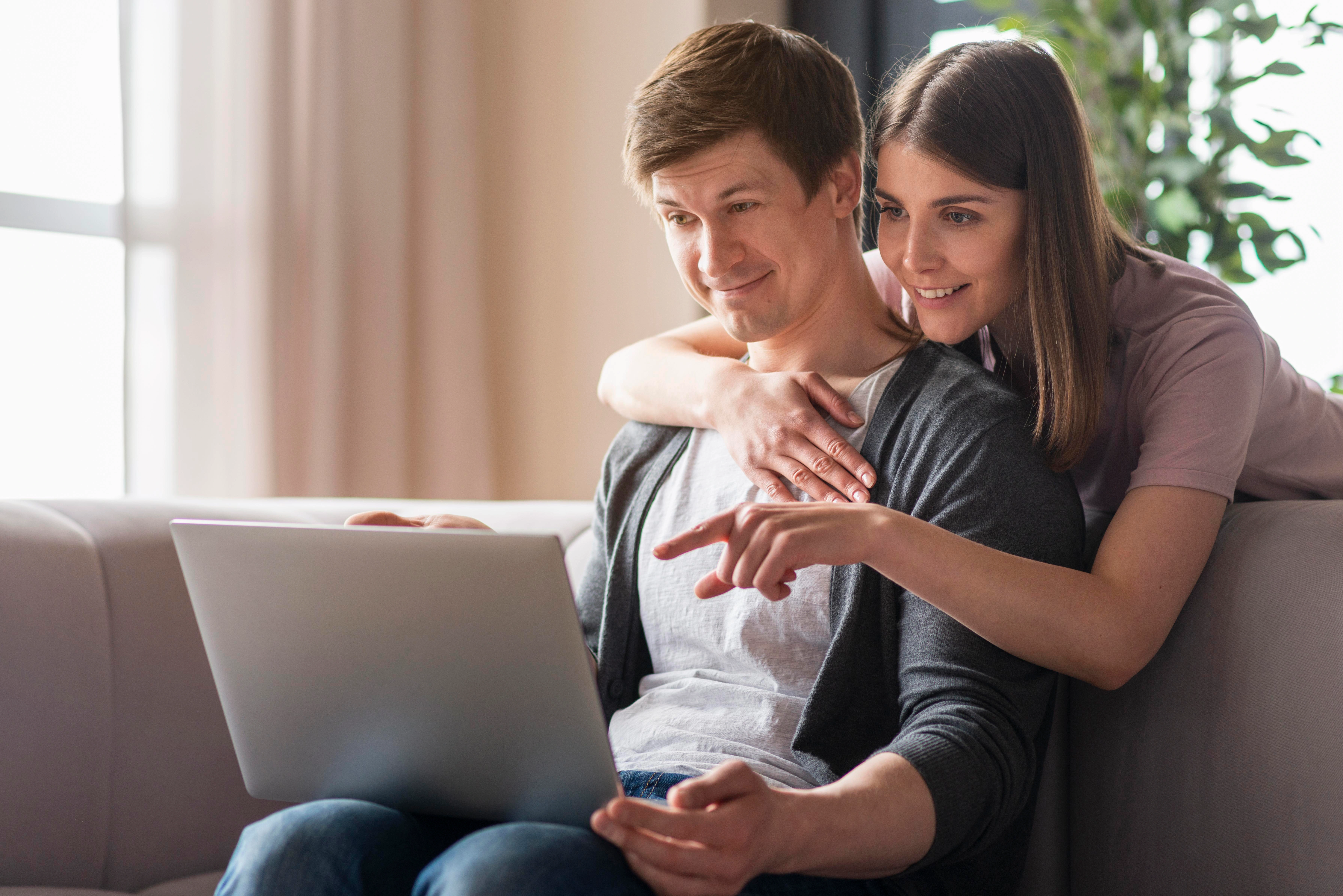 Pareja joven usando el panel de invitados de Weddeb en su laptop para organizar su boda.